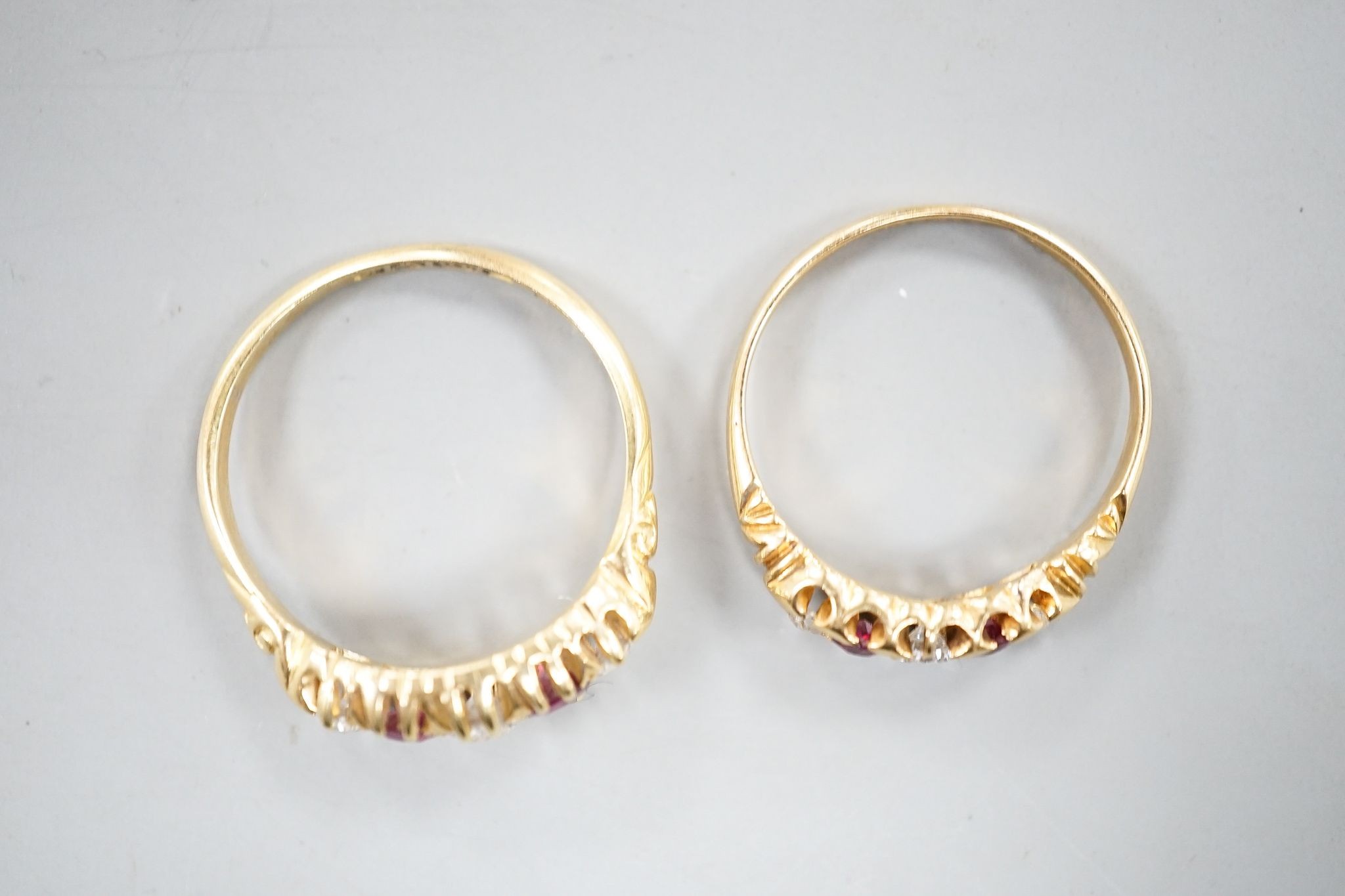 Two early 20th century 18ct gold, ruby and diamond five stone set half hoop rings, sizes m and P/Q, gross weight 5.1 grams.